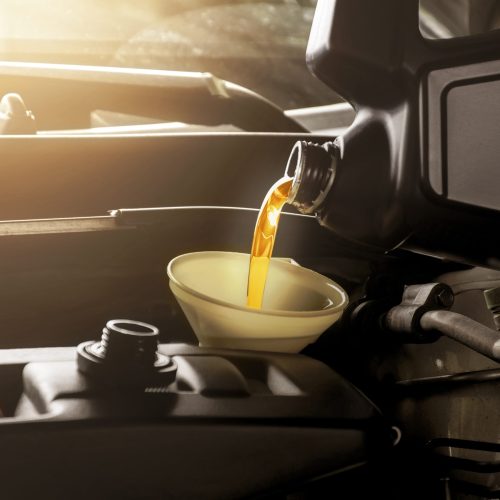 Mechanic man pouring engine oil to car engine